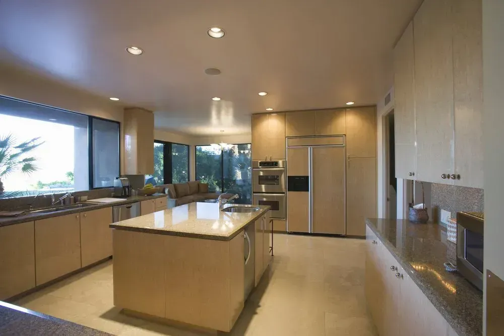 Modern kitchen with large island, stainless appliances, wood cabinets, and a bright window view