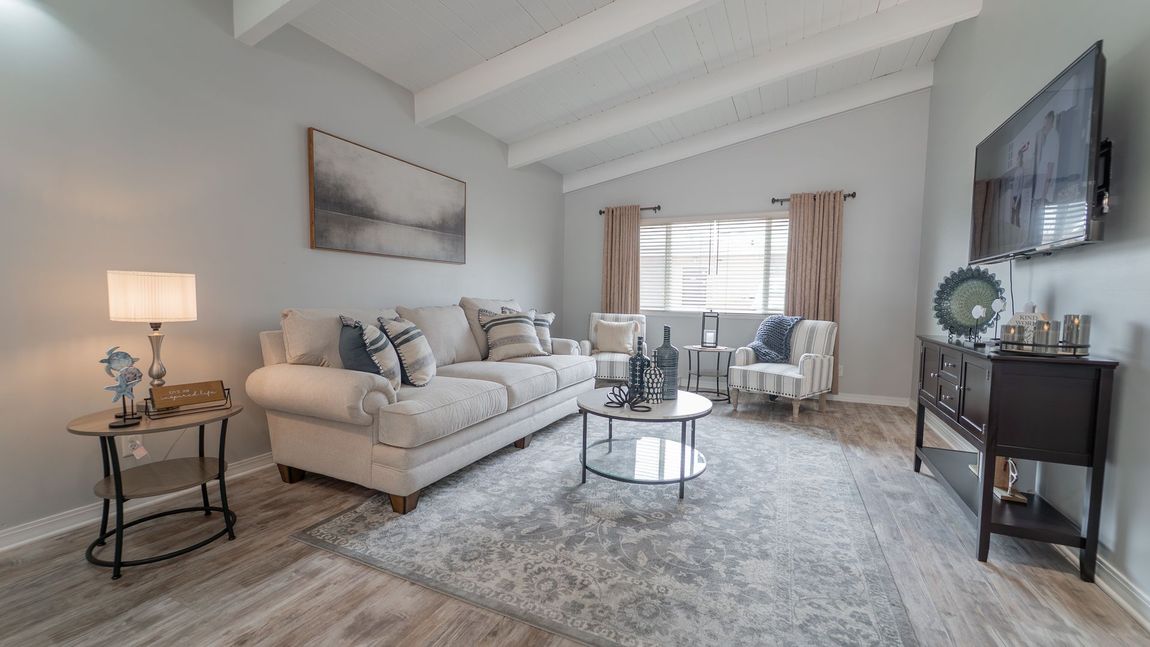 Living room with gray walls, white ceiling beams, and light-colored furniture.