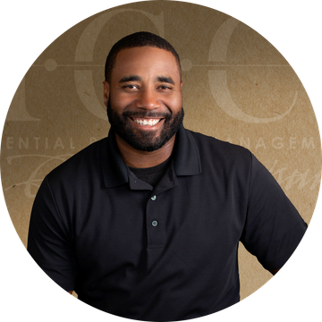Smiling man in black polo shirt against a textured background.