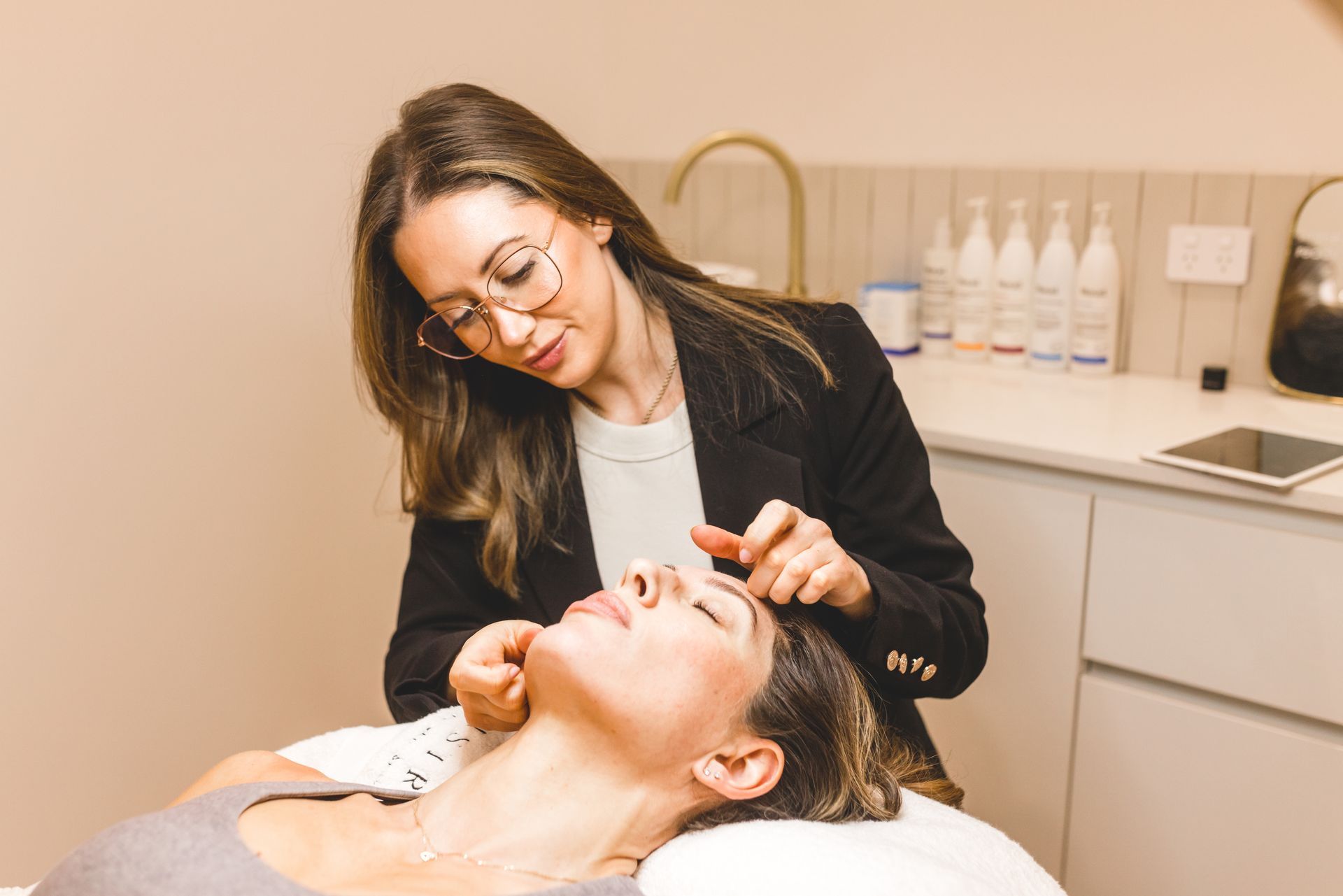 Tijan of Aesthetic Artistry assessing a client's face
