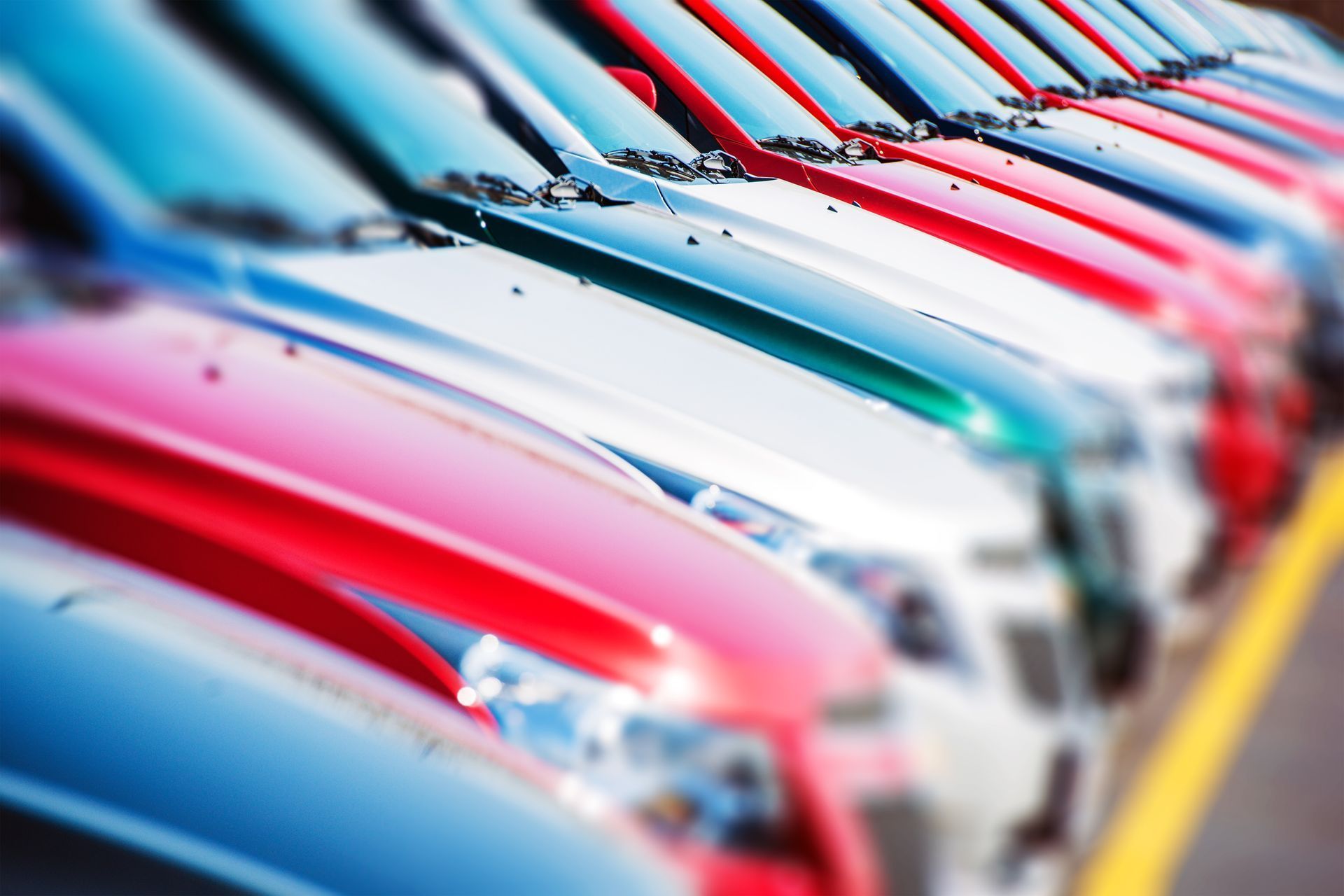 Row of colorful cars parked in a dealership lot, partially blurred | Custom Performance Center