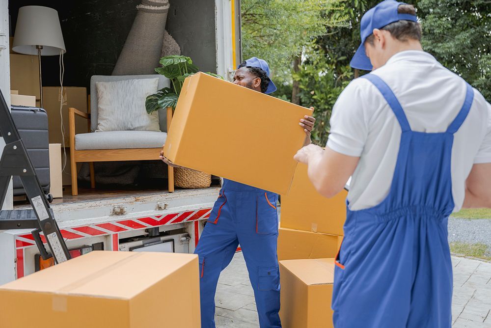 Two men movers worker in blue uniform unloading cardboard box into the truck. Professional delivery