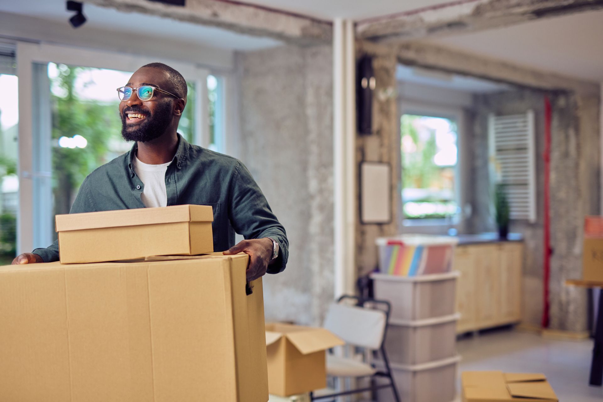 Smiling businessman carrying cardboard boxes in new office during relocation. Smiling businessman carrying cardboard boxes in new office during relocation.