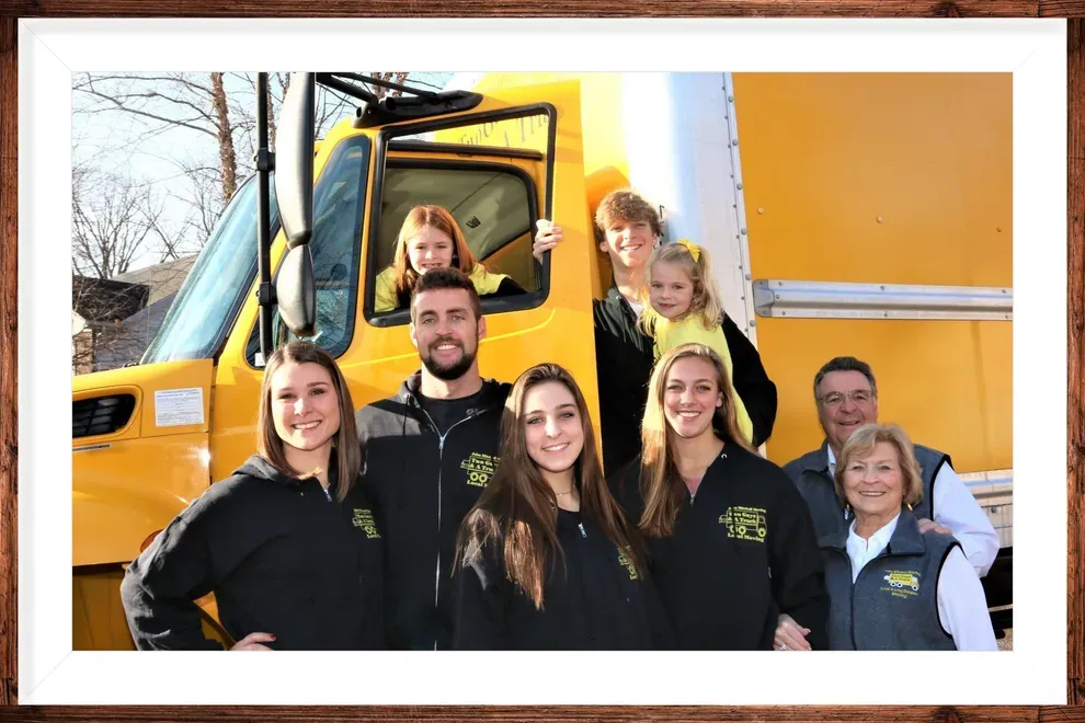 Family With Yellow Truck — Anderson, IN — John Mitchell Moving Two Guys & A Truck A group outside a residential moving truck in Muncie, IN