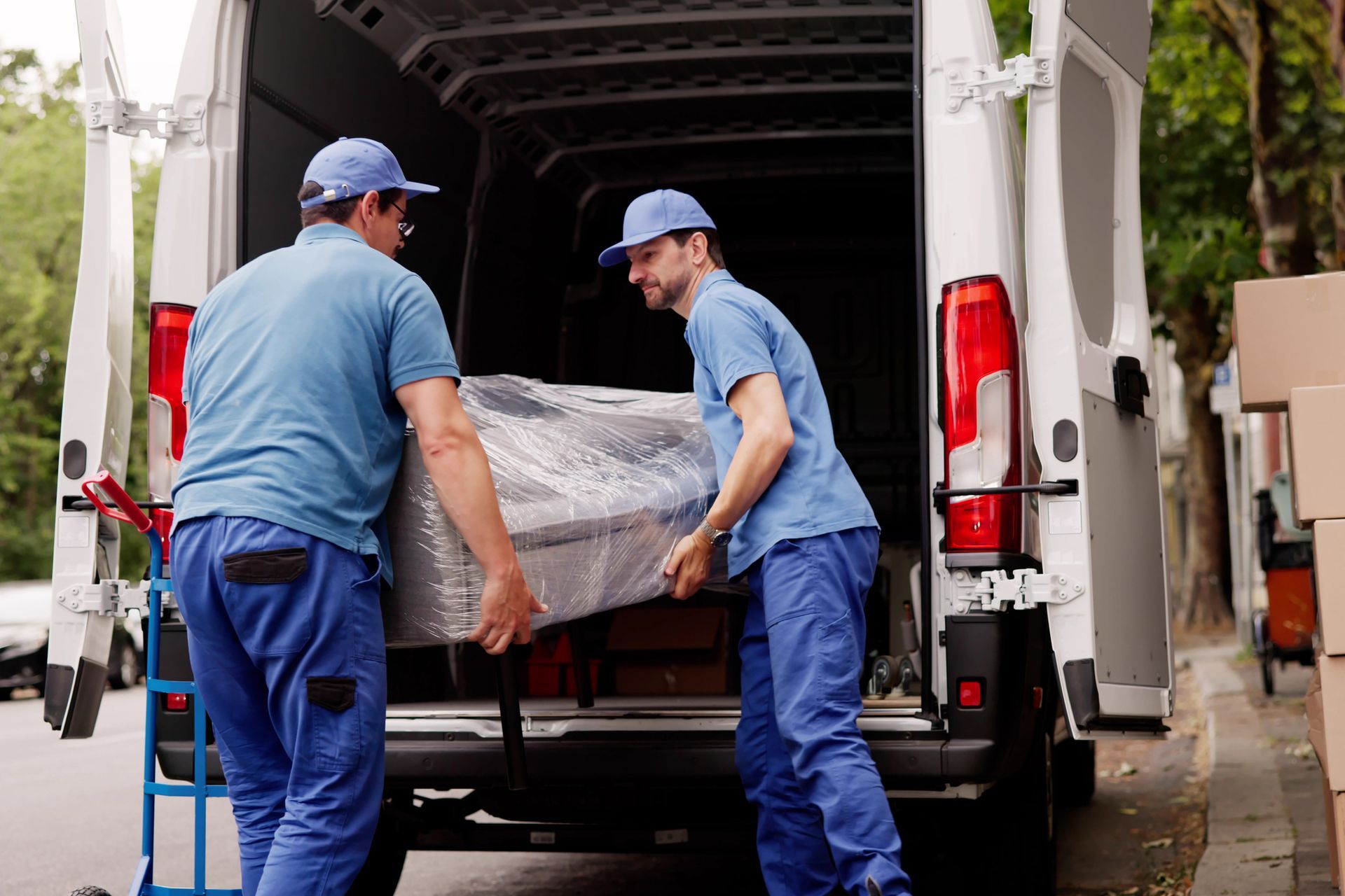 Professional movers loading wrapped furniture into a delivery van during relocation.