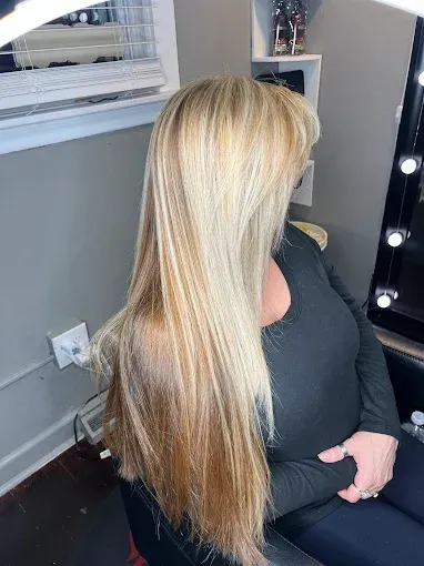 Long blonde hair with highlights, viewed from the side, worn by a person in a black long-sleeved shirt.