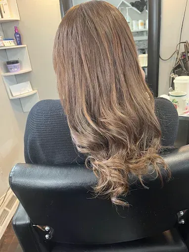 Long brown hair with soft curls, viewed from behind in a salon setting.