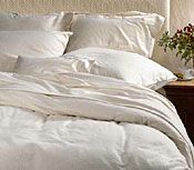 A bed with a white comforter and pillows on it.