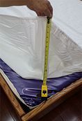 A person is measuring a mattress with a tape measure.