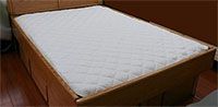 A white mattress is sitting on top of a wooden bed.