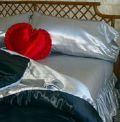 A bed with a heart shaped pillow on top of it.