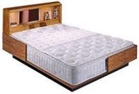 A bed with a mattress and a wooden headboard.