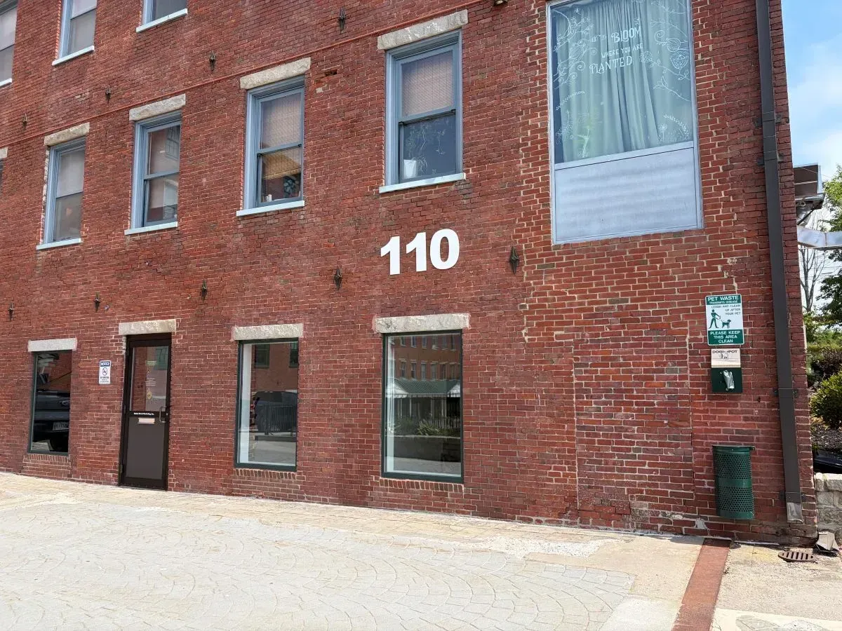 Brick apartment building entrance with number 110 and an orange car parked outside.