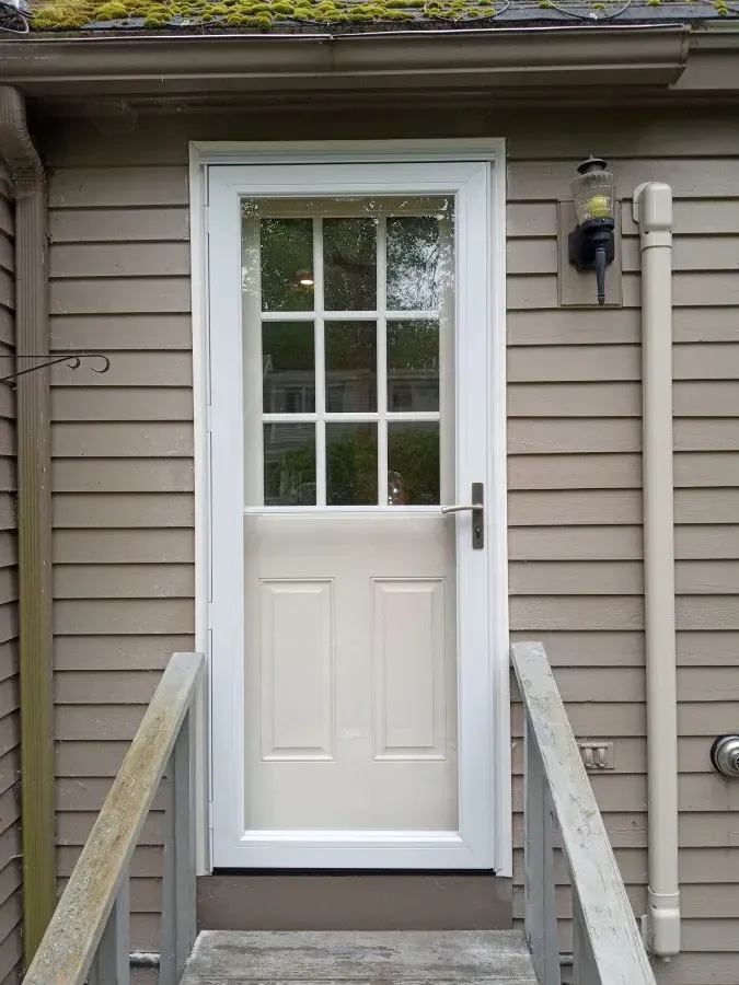 A white door with a window is on the side of a house.