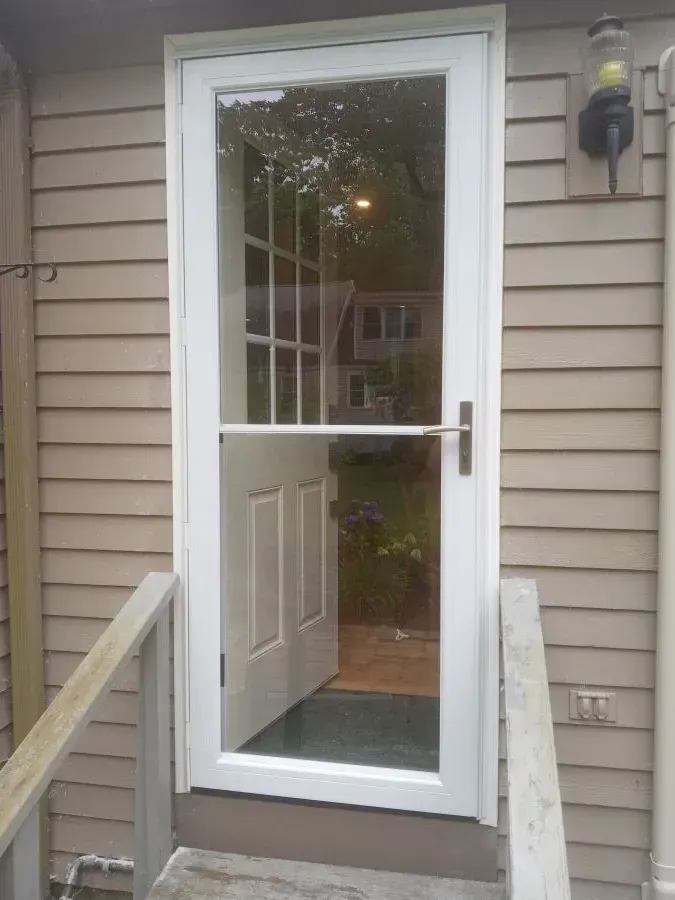 A white door with a glass window is on the side of a house.