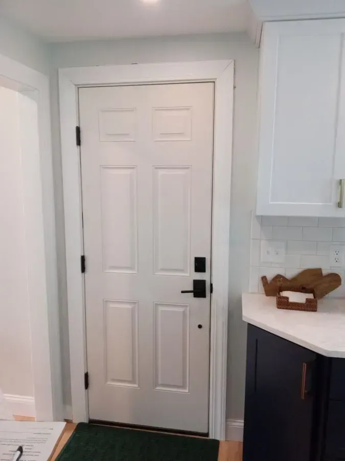 A white door with a black handle is in a kitchen.