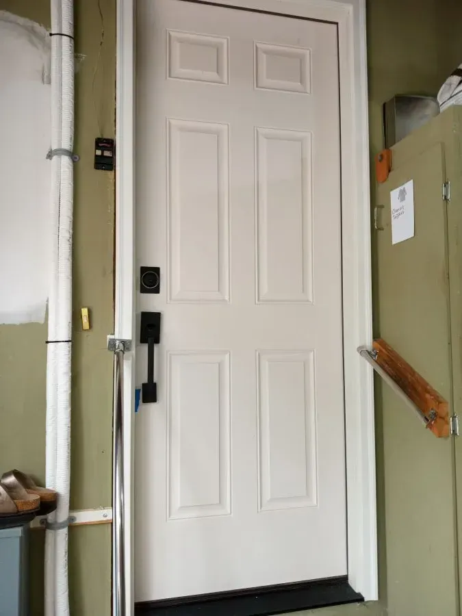 A white door with a black handle is in a room.