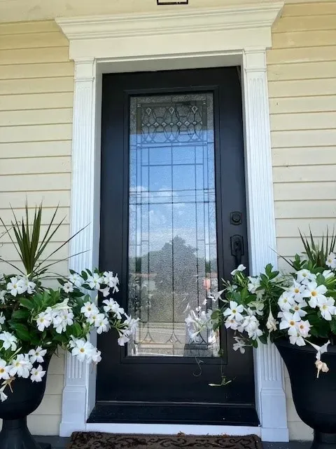 A black door with white flowers in front of it