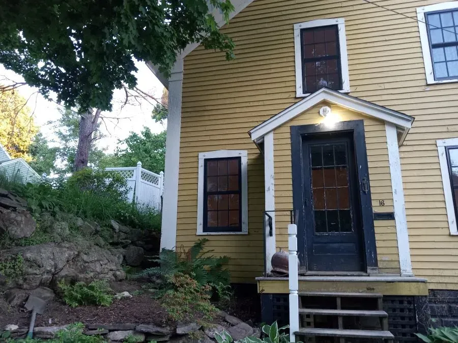 A yellow house with a black door and a porch