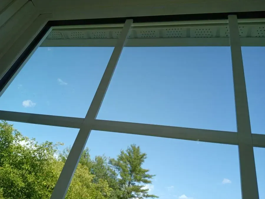 A window with a blue sky and trees in the background