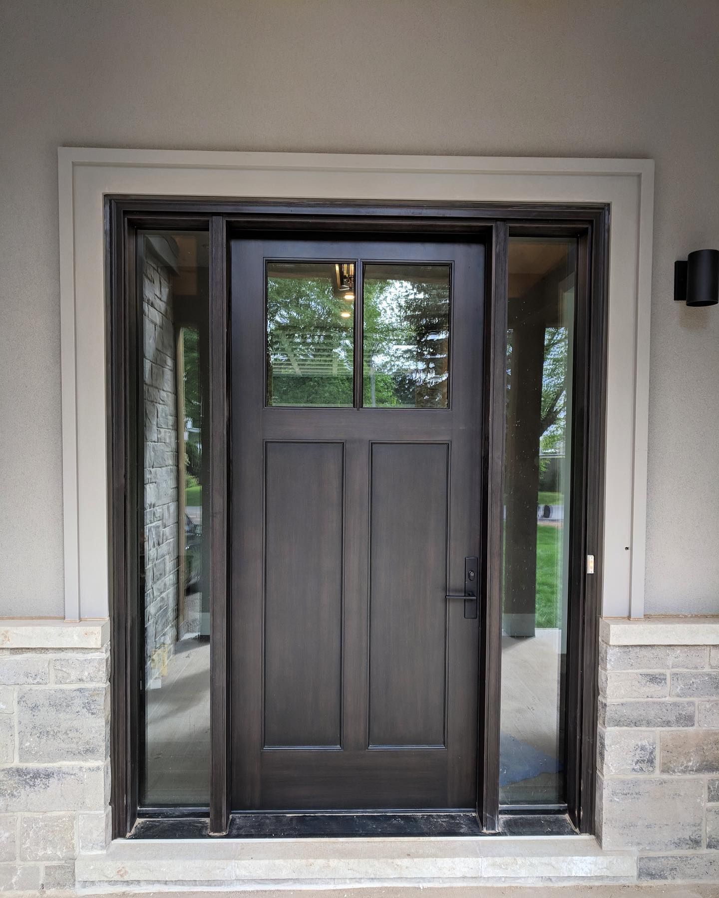 Dark wooden front door with glass panels, centered in a light gray doorway.