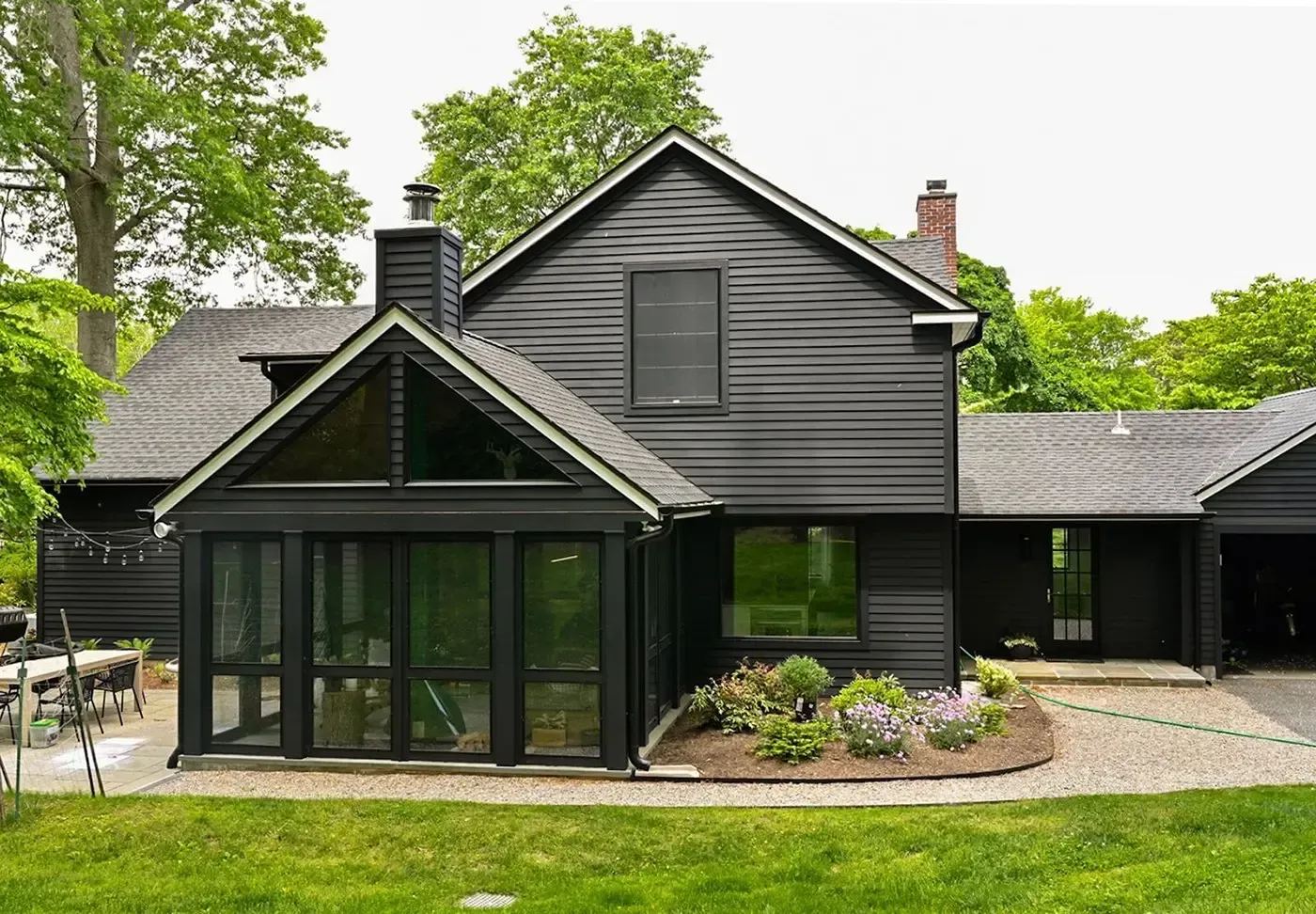 Dark gray house with screened porch, gabled roof, and landscaped front yard