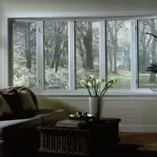 Living room with a large window overlooking a wooded yard, with a sofa and coffee table in the foreground