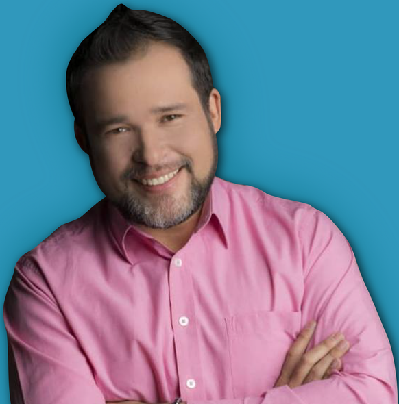 Hombre con barba y camisa rosa sonriendo con los brazos cruzados, sobre un fondo verde azulado.