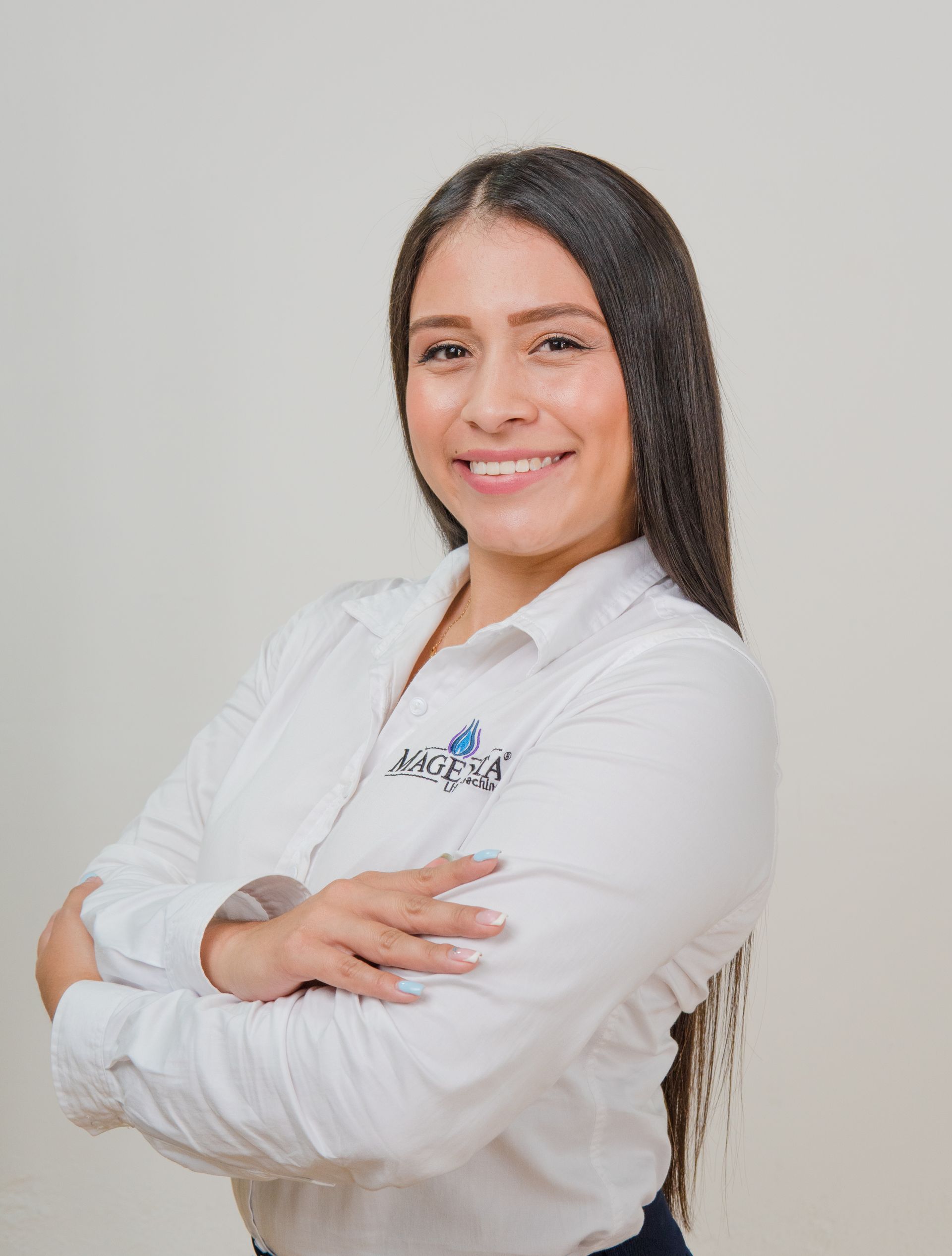 Mujer con camisa blanca con los brazos cruzados, sonriendo, logo en la camisa.