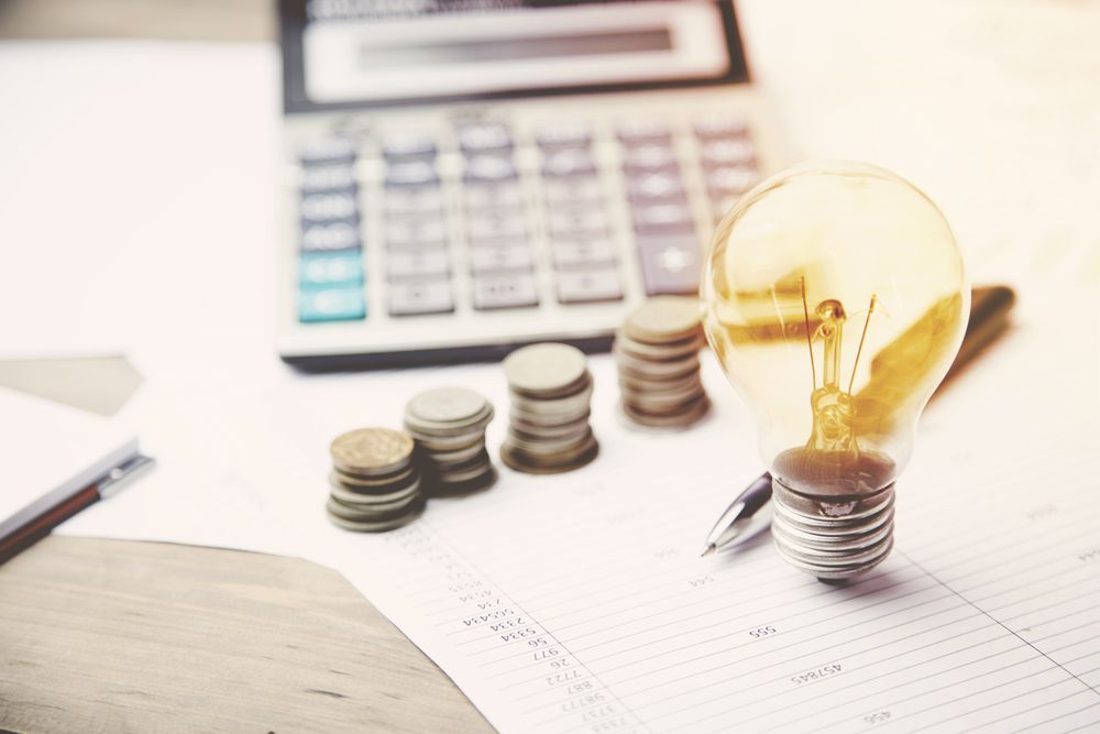 Light Bulb, Stacks of Coins and a Calculator Sitting on Top of a Table — Forsyths Accounting Services Pty Ltd in Mackay, QLD