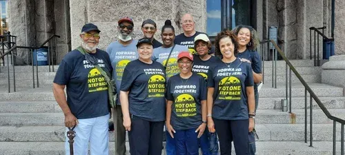 Group of volunteers in matching navy shirts posing on courthouse steps