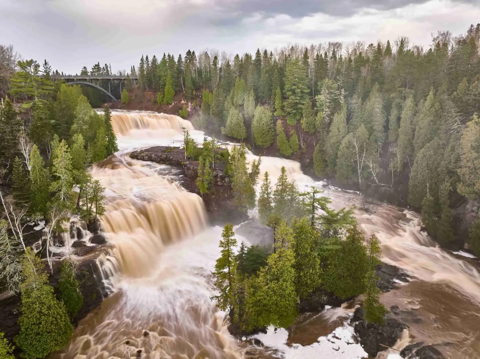 A waterfall is surrounded by trees and rocks in the middle of a forest.