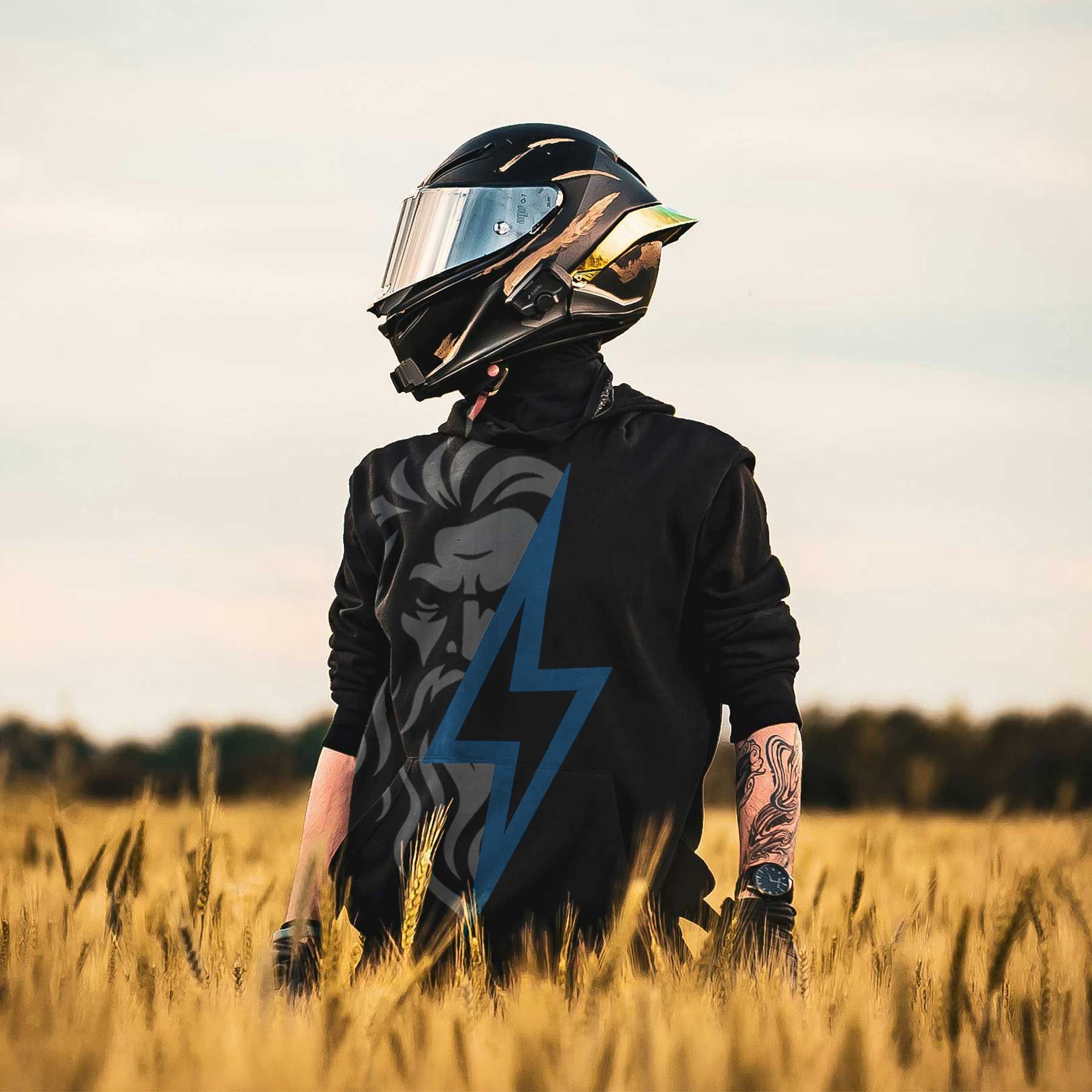 Motorcyclist in a black jacket and helmet standing in a wheat field at sunset