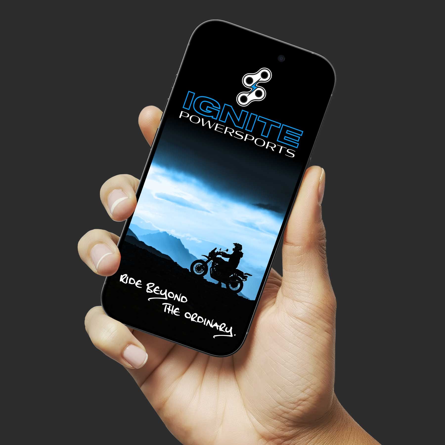 Hand holding a black smartphone with a mountain bike wallpaper and the word “IGNITE” on screen