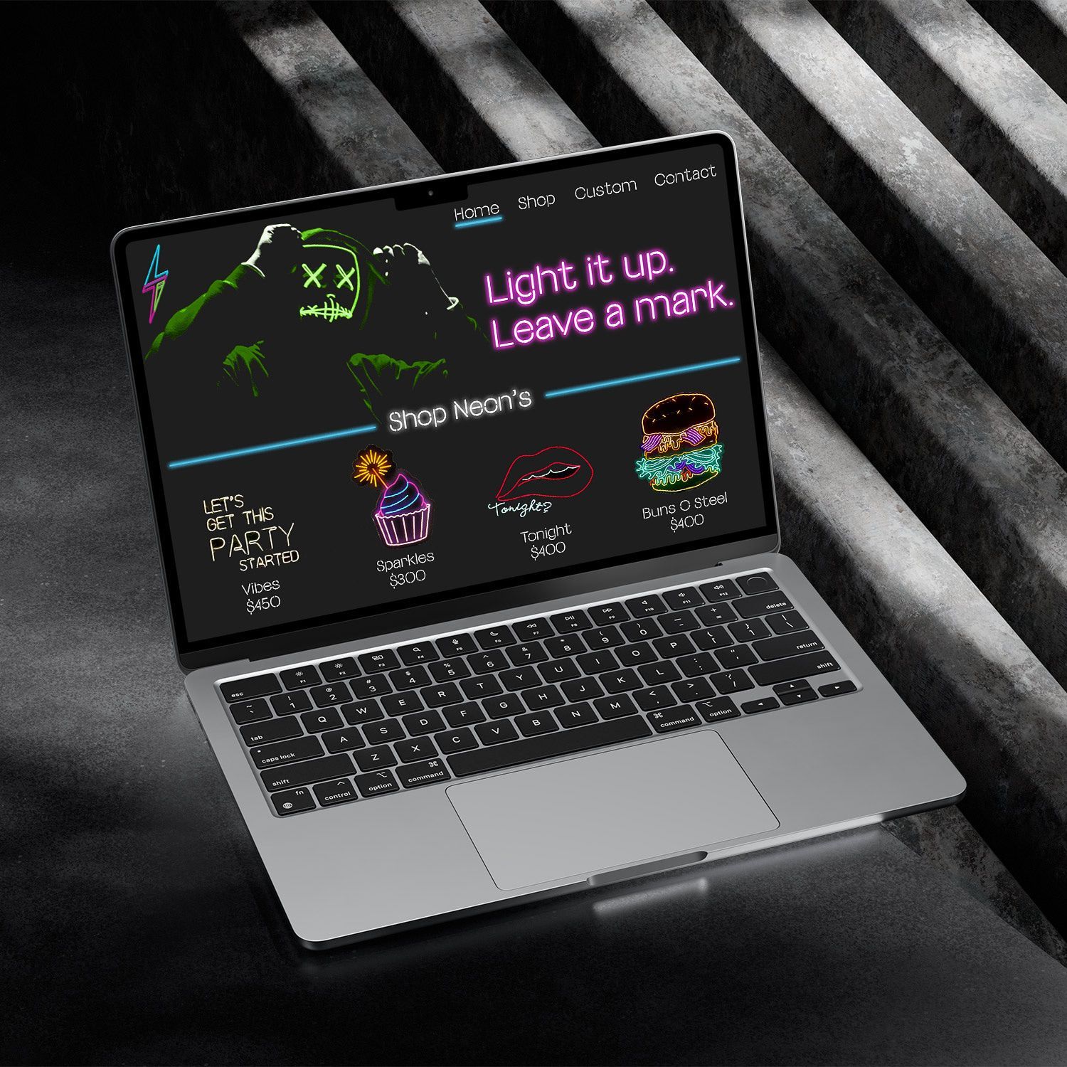 Open laptop on dark striped surface showing a neon-themed screen with “Leave a mark” text