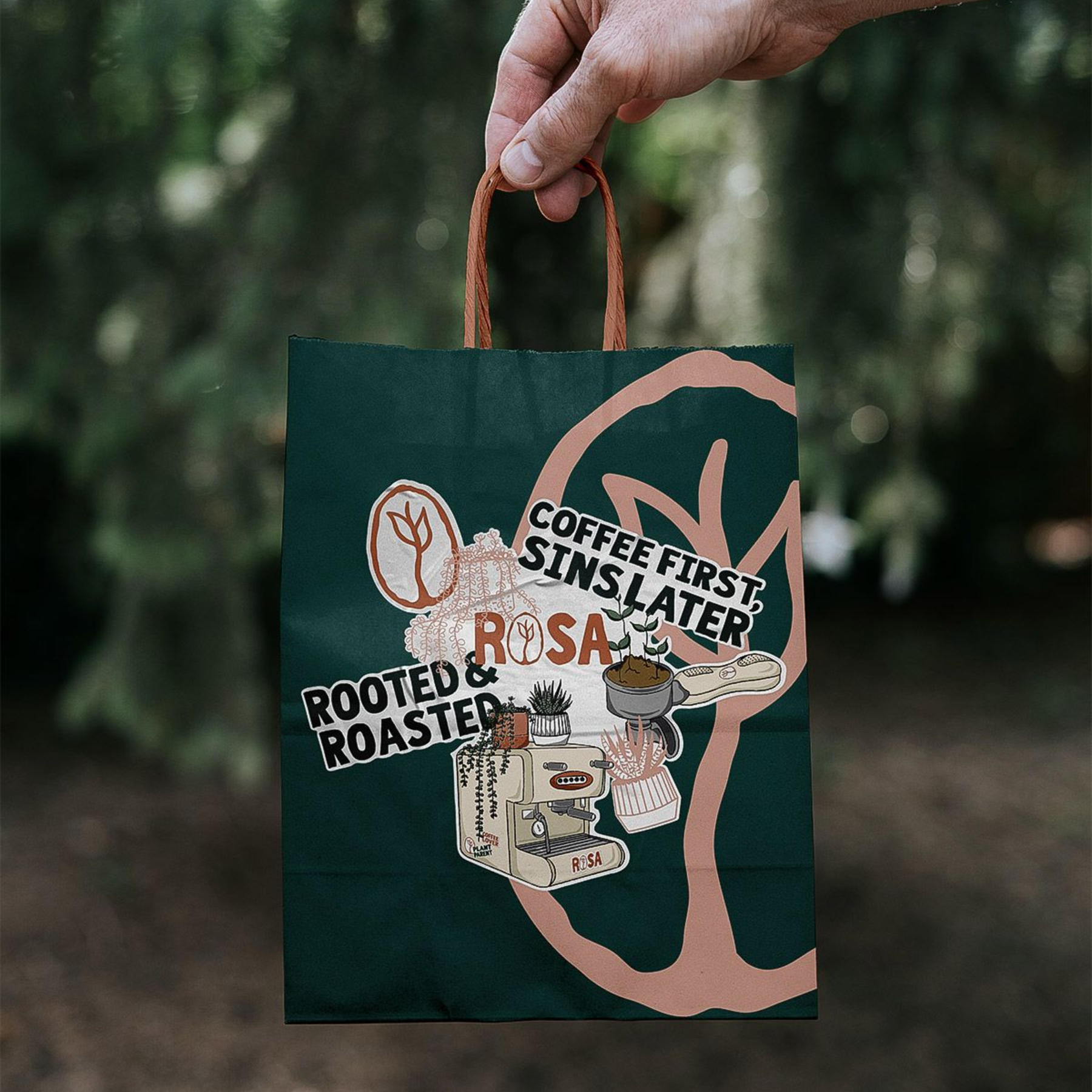 Hand holding a dark green tote bag with graphic text and a coffee-themed design
