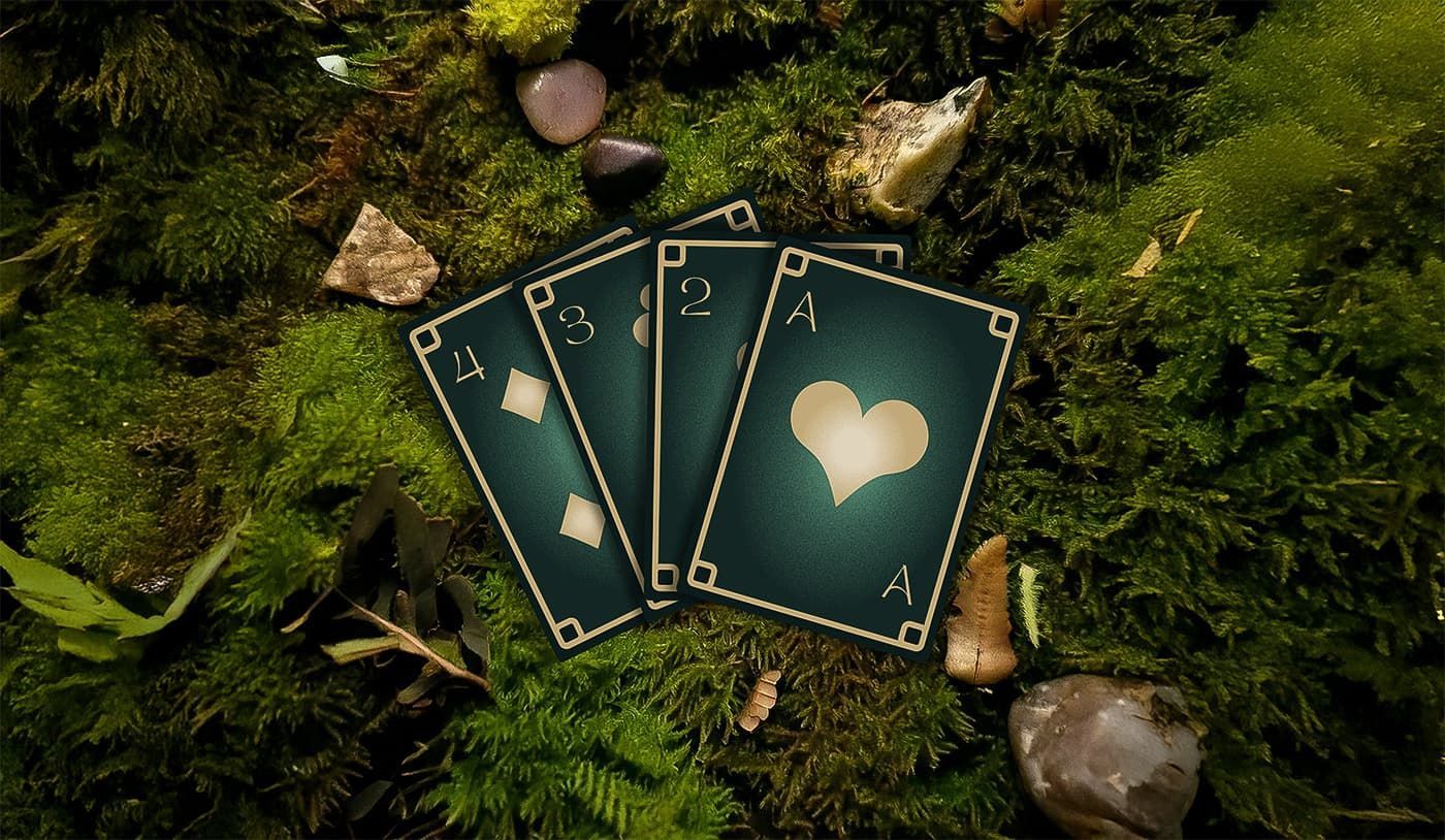 Playing cards with glowing heart symbols arranged on mossy ground with small stones