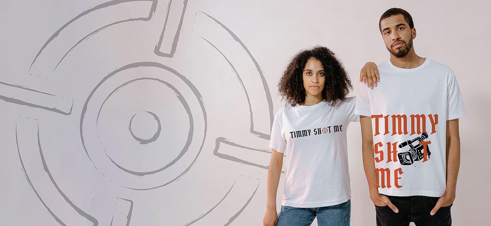 Two models wearing graphic T-shirts stand before a white wall with a circular line design.