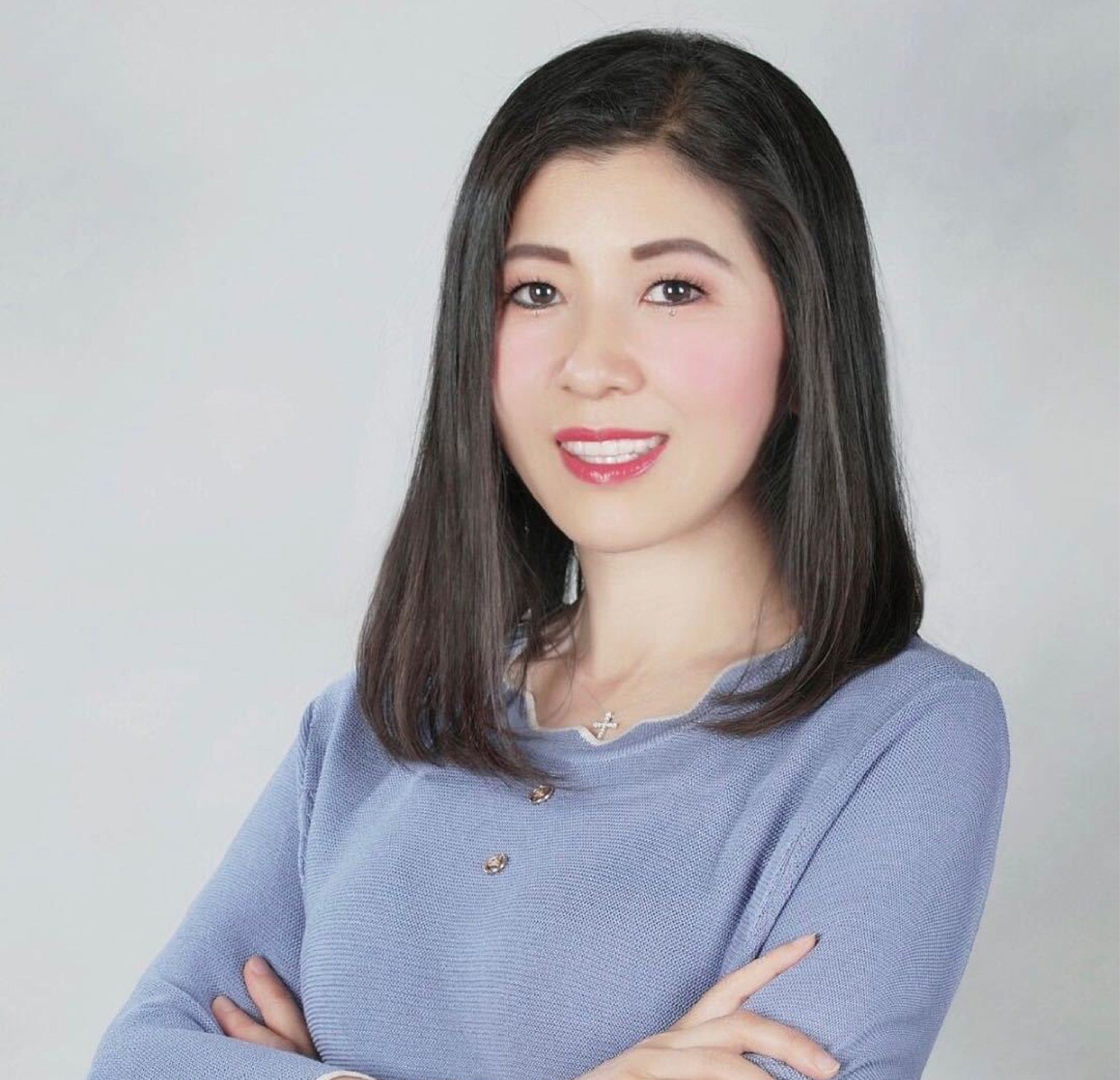 A woman in a blue sweater with her arms crossed
