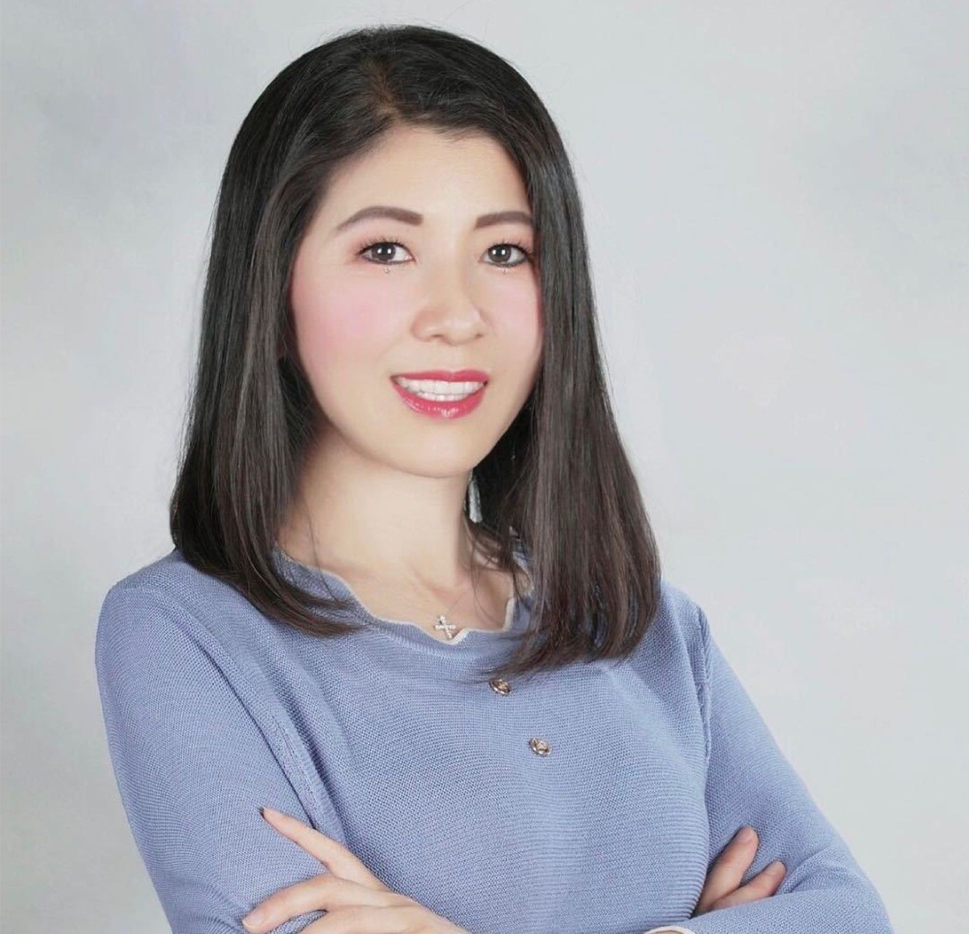 A woman in a blue sweater with her arms crossed