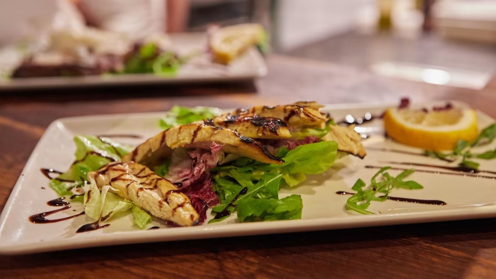 Formaggio halloumi grigliato e insalata con spicchio di limone su un piatto bianco.