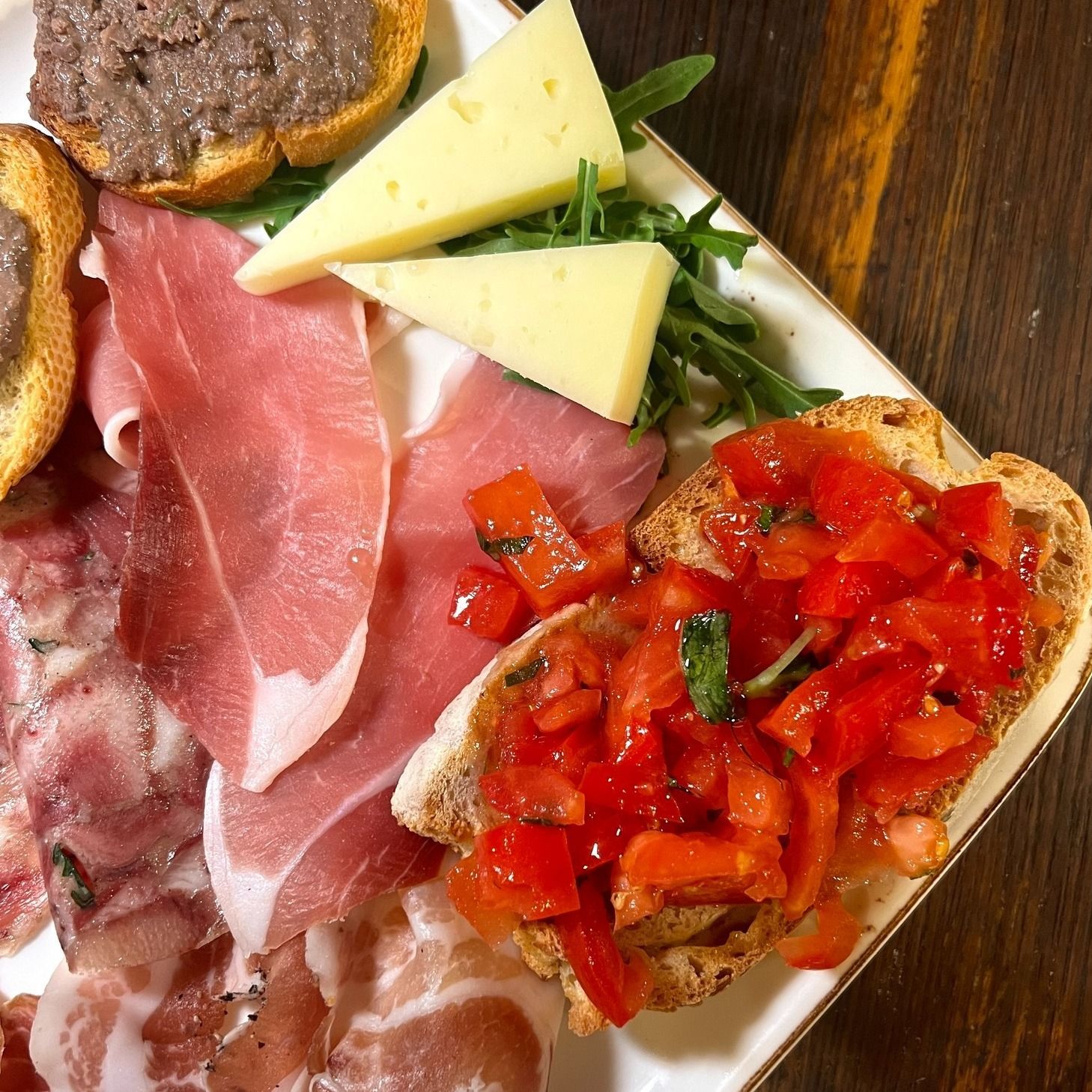 Tagliere di salumi con carne, formaggio, pane e condimento al pomodoro.