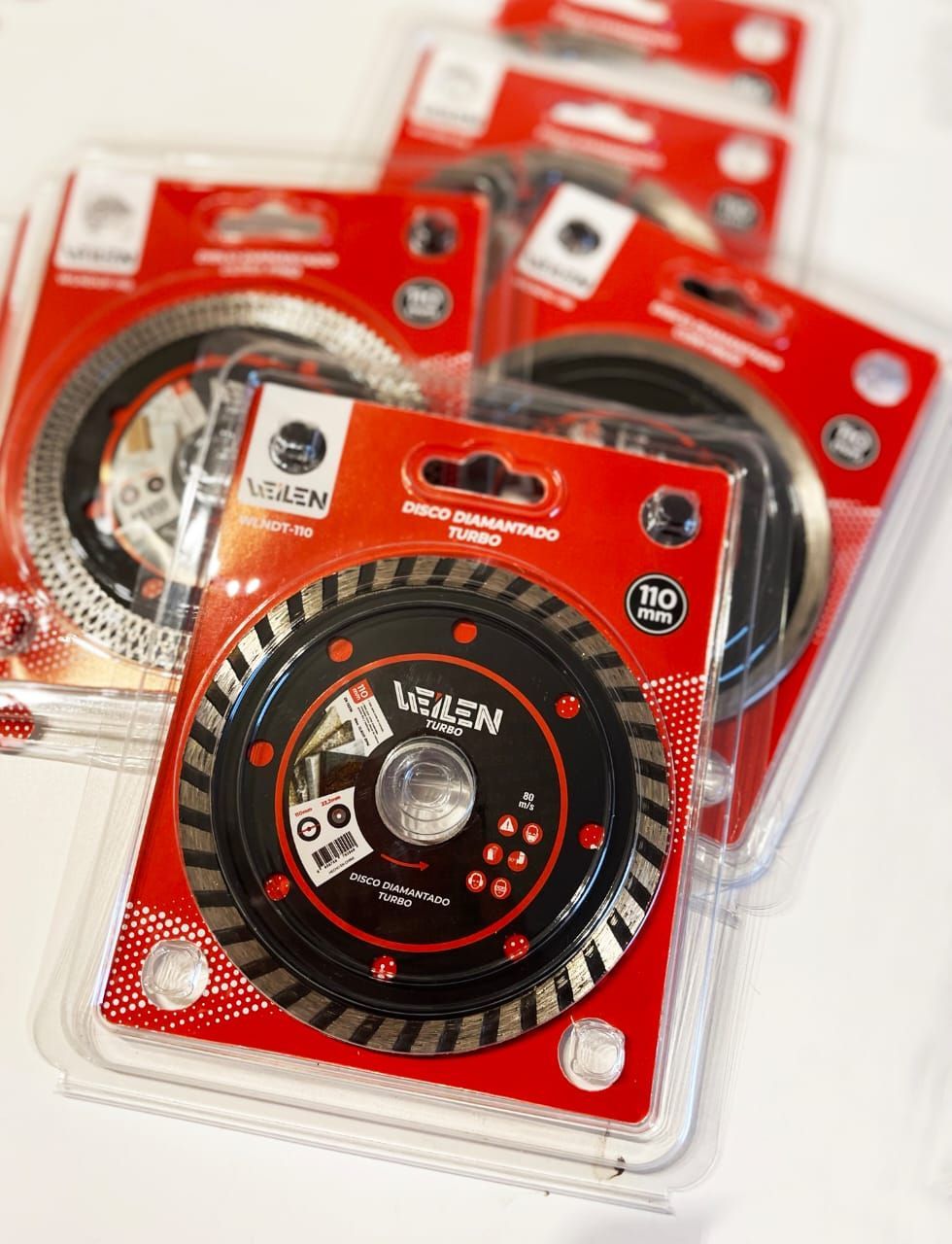 Varias hojas de sierra circular empaquetadas, rojas y negras, expuestas para la venta.