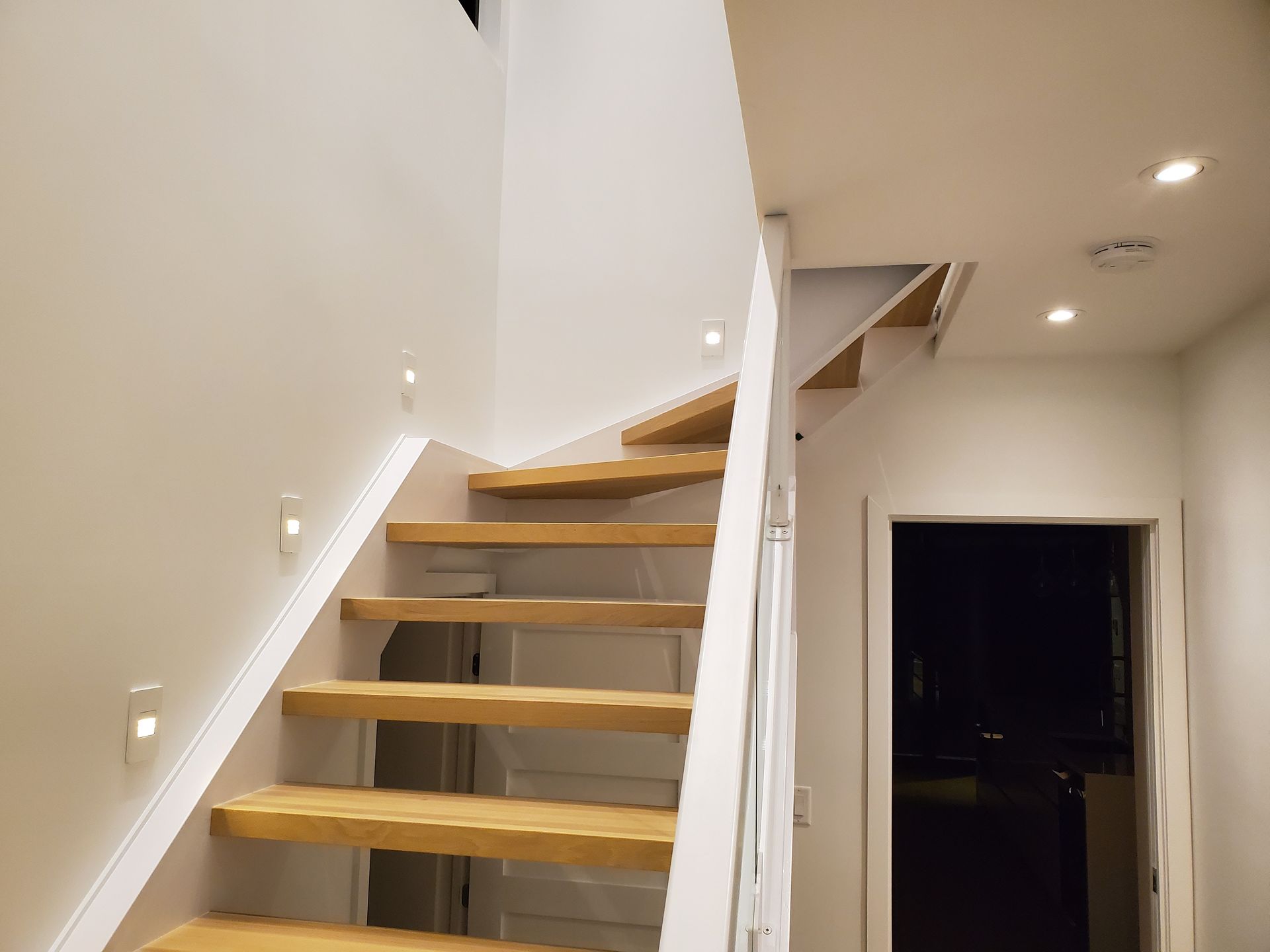 Un escalier en bois avec une rampe blanche dans un couloir