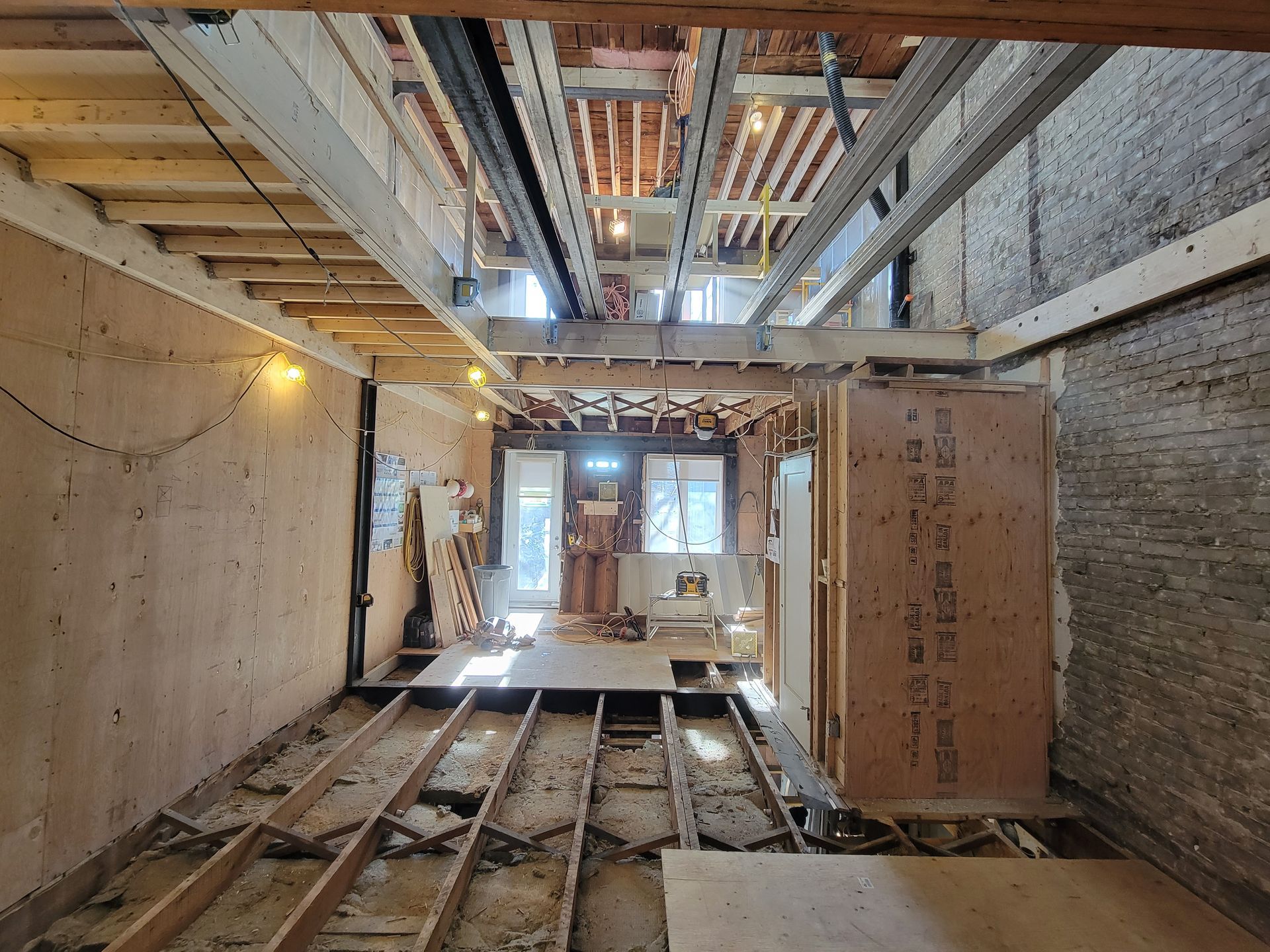 Une pièce avec un plancher en bois et un mur en briques en construction.