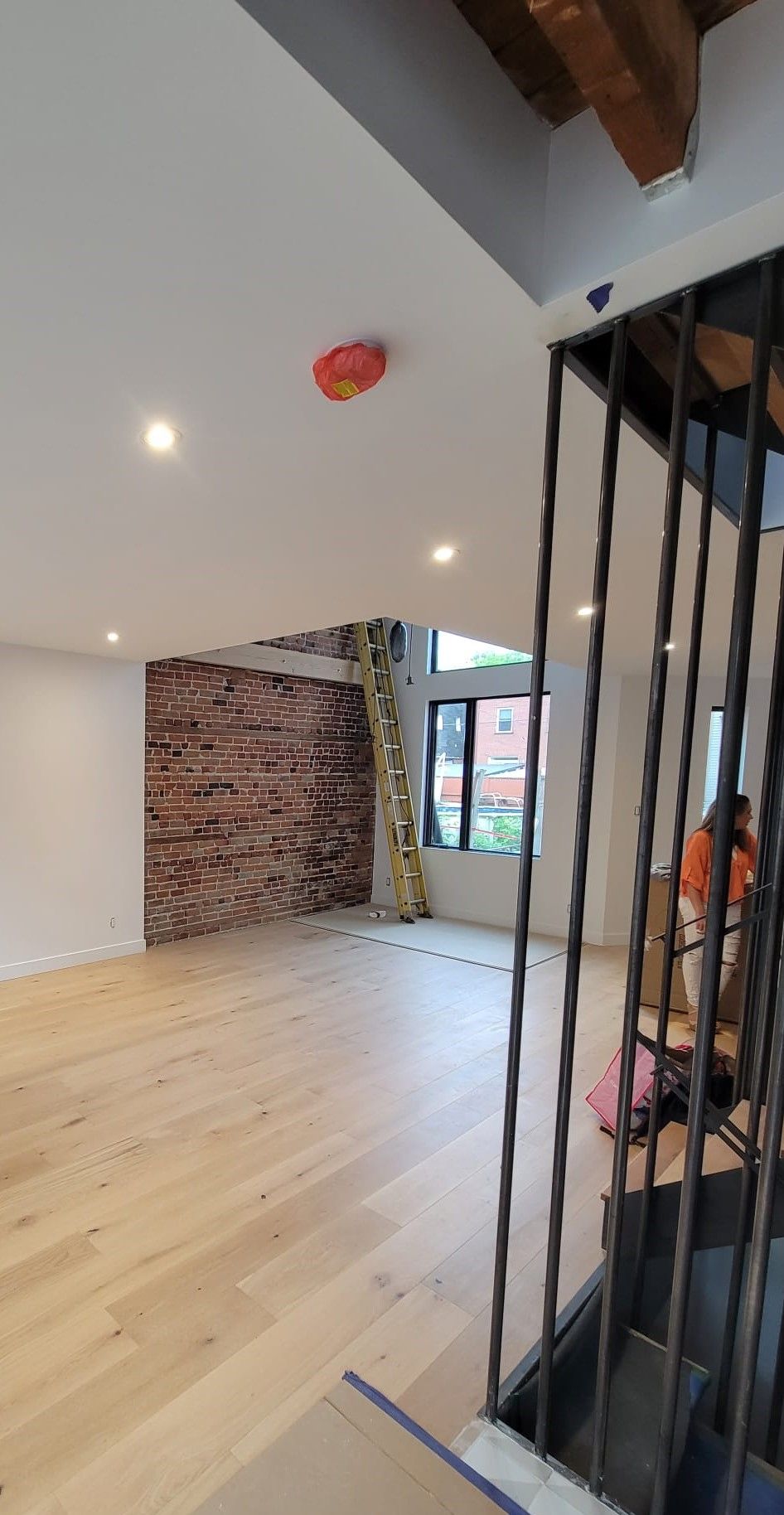 Une grande pièce vide avec du parquet et un escalier.