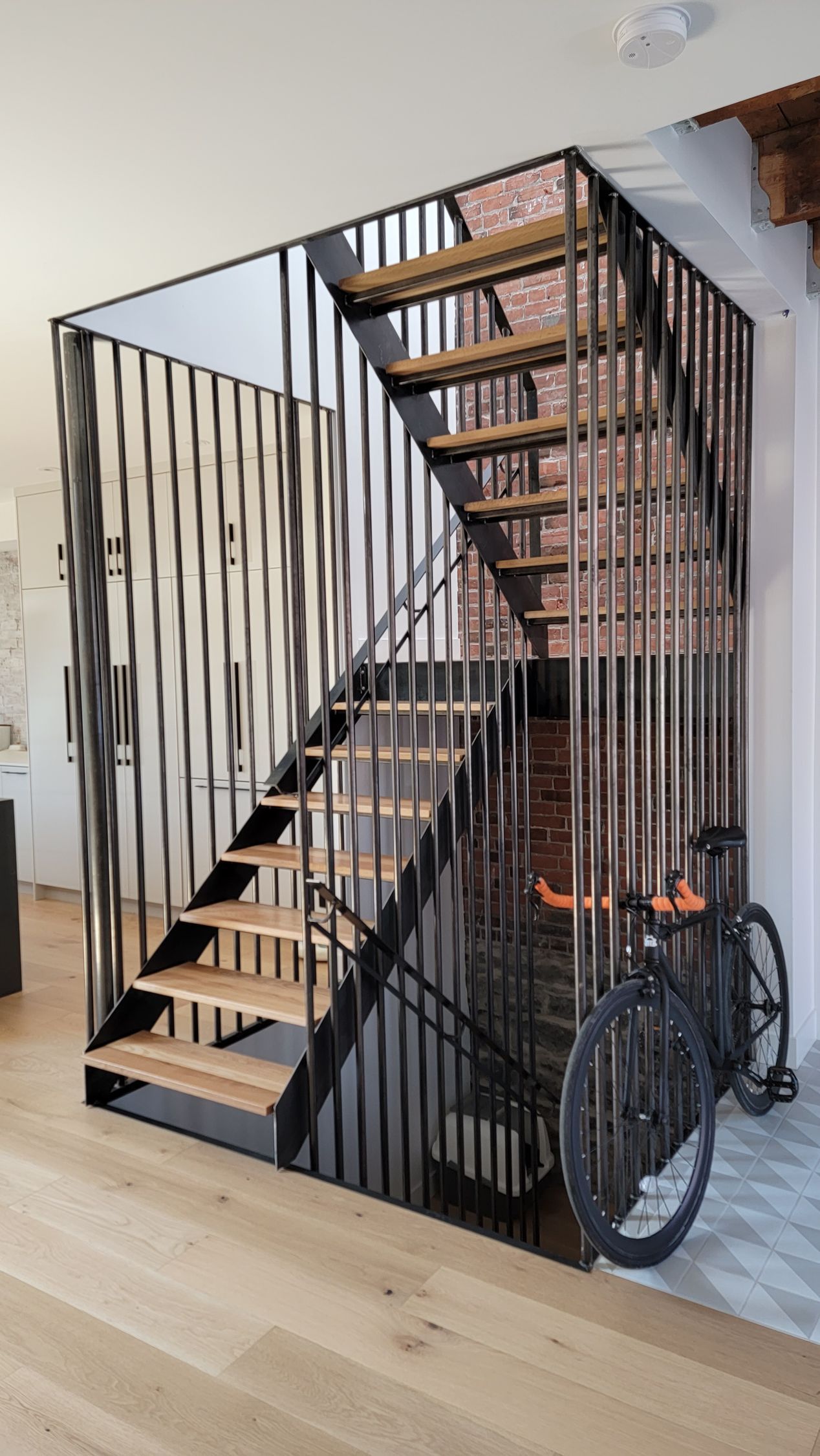 Un vélo est garé sous un escalier dans une maison.