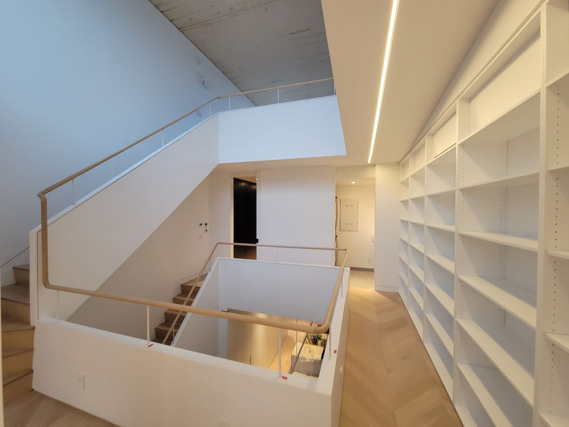 Il y a un escalier au milieu d'une pièce avec des étagères.