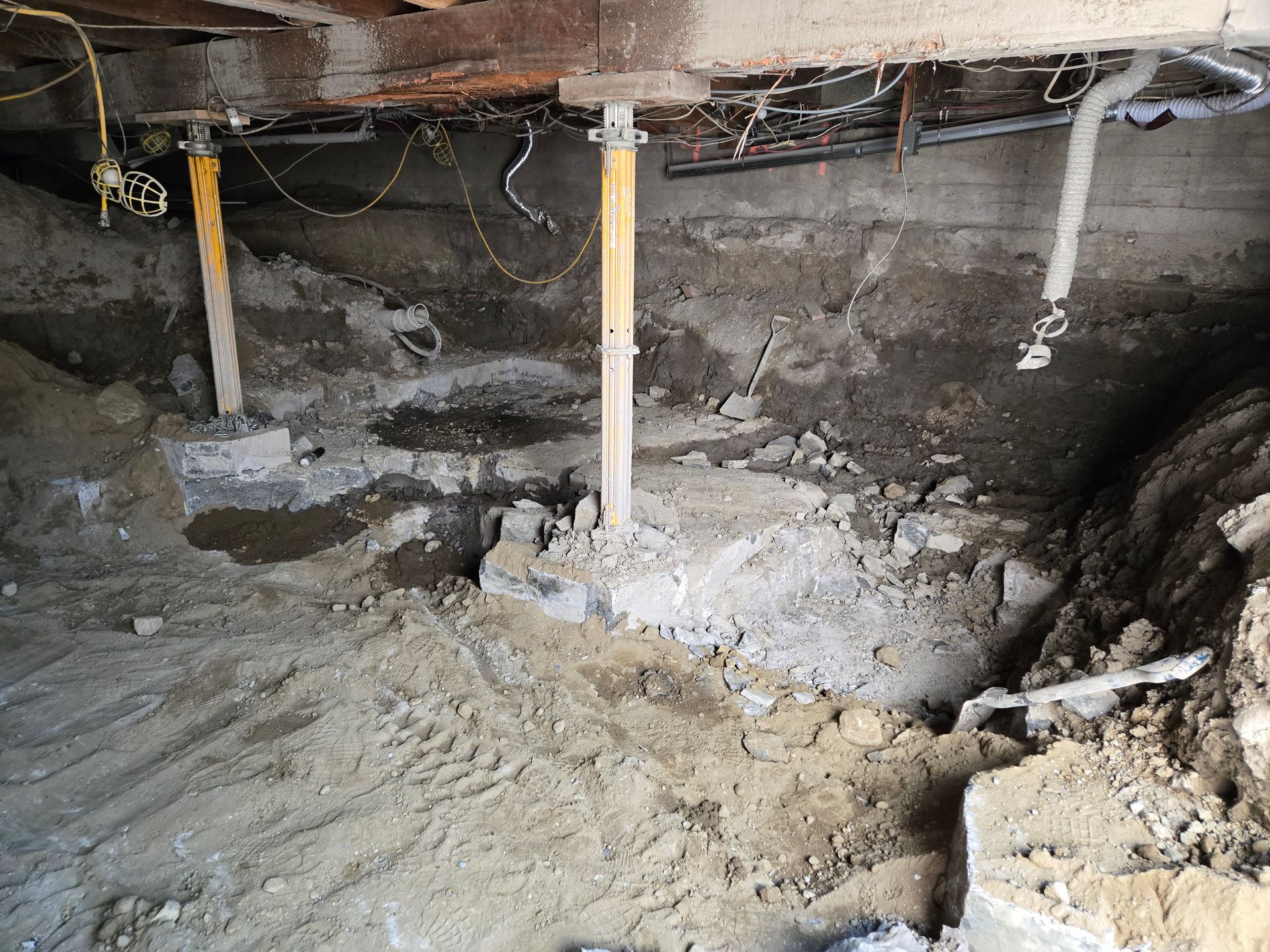 Intérieur d'un bâtiment en rénovation avec murs en pierre apparents, poutres en bois, équipement de construction et débris au