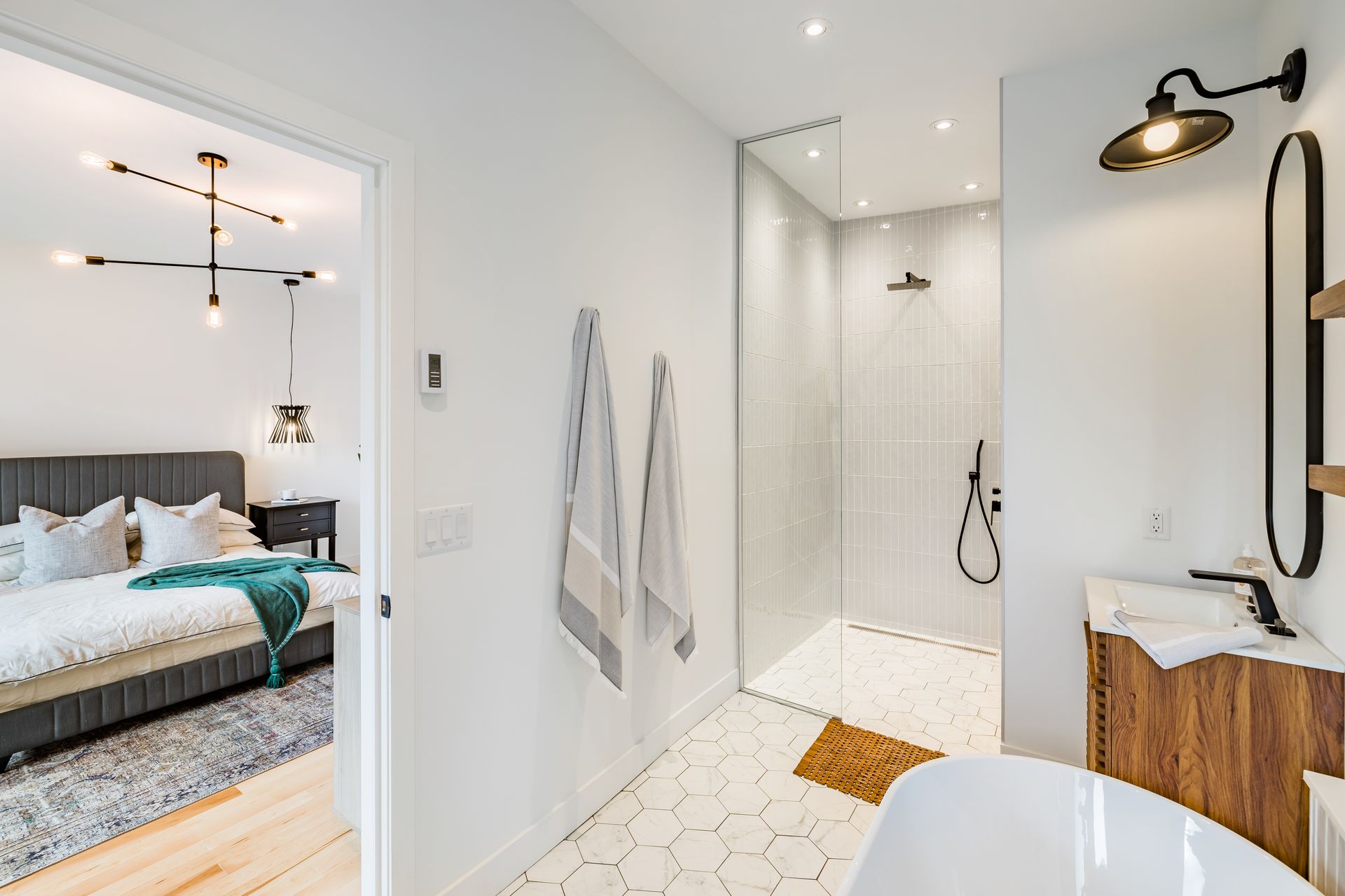 Une salle de bain avec baignoire et douche à l'italienne attenante à une chambre.